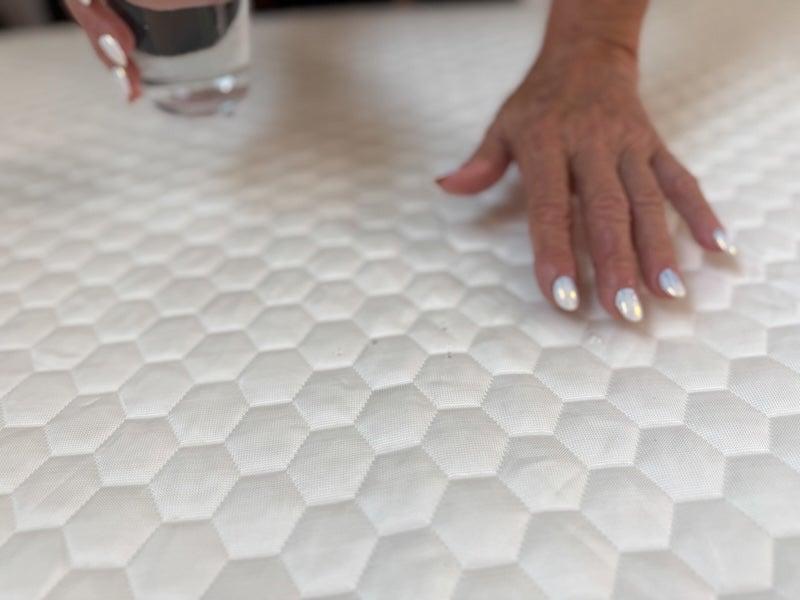 A woman presses down on the quilted surface of the Brooklyn Bedding Luxury Cooling Mattress Protector