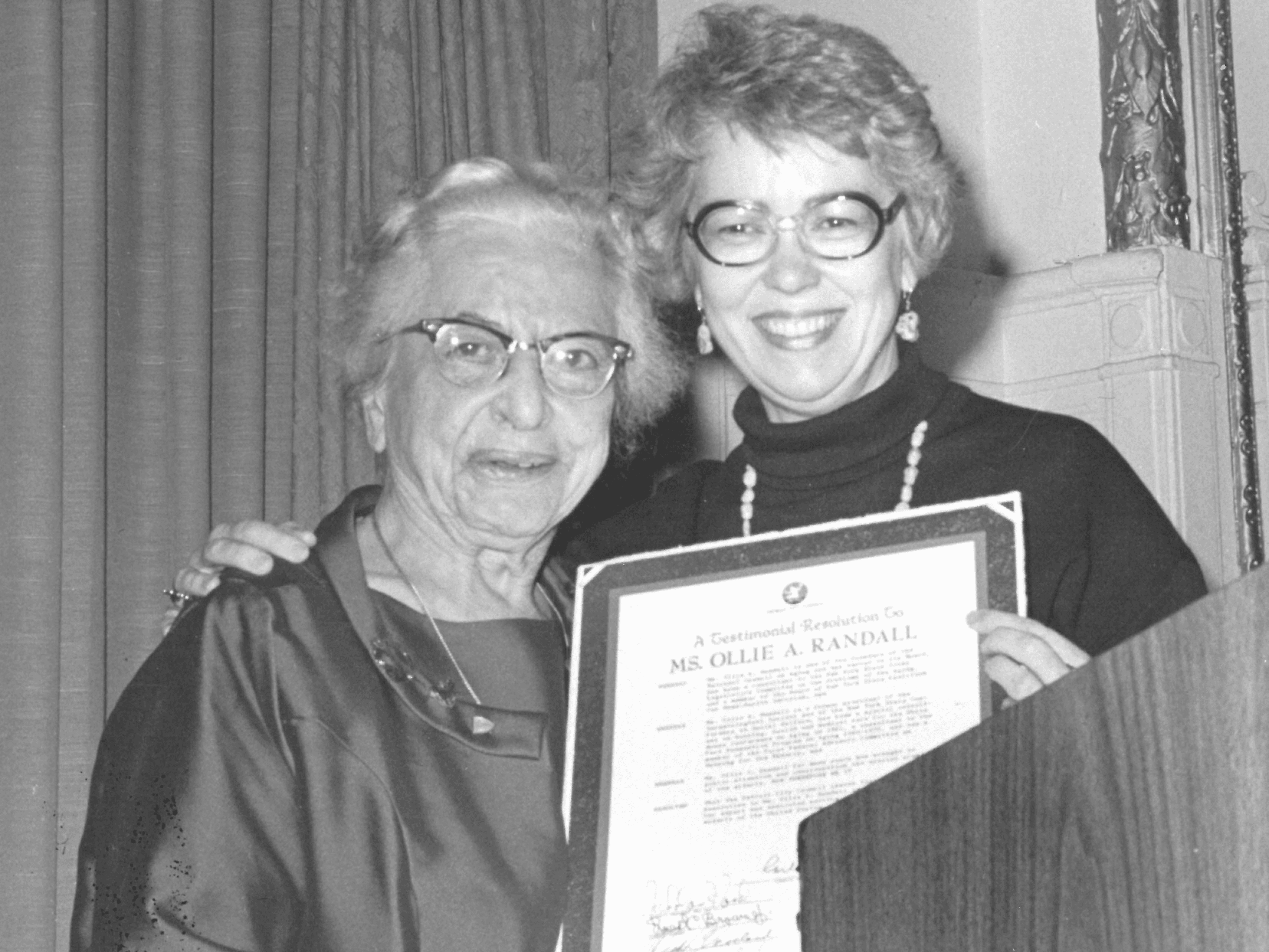 Ollie Randall receiving an award at lectern from smiling woman in glasses