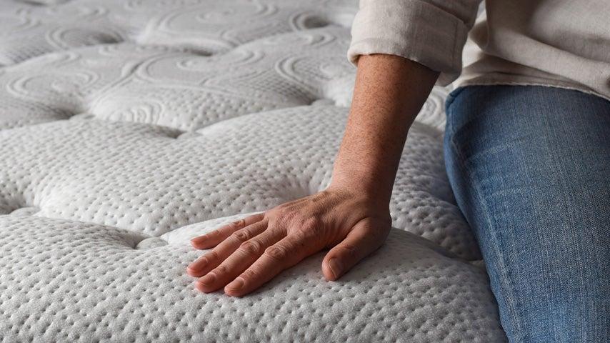 woman's hand on mattress