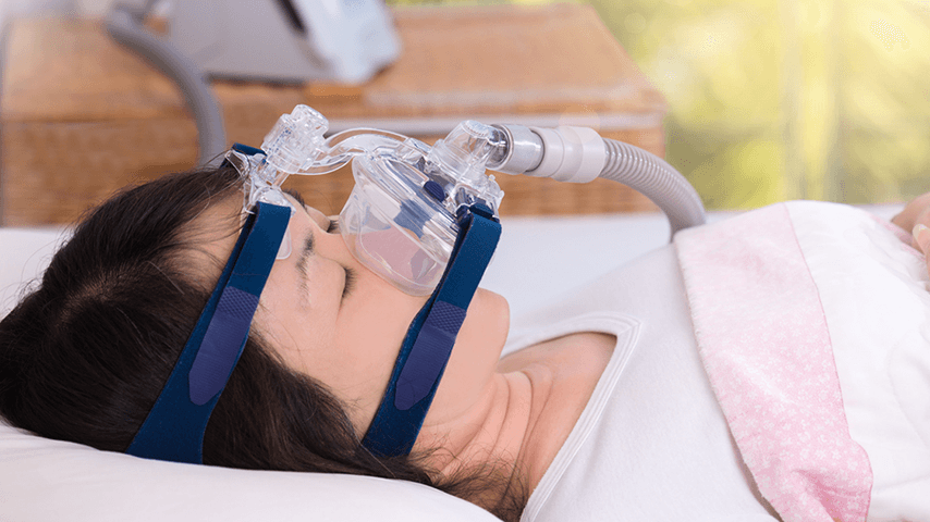 Asian woman asleep with CPAP mask on