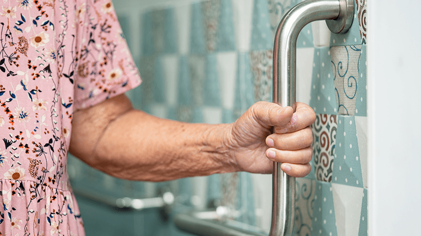 older woman's hand around a bathroom grab bar