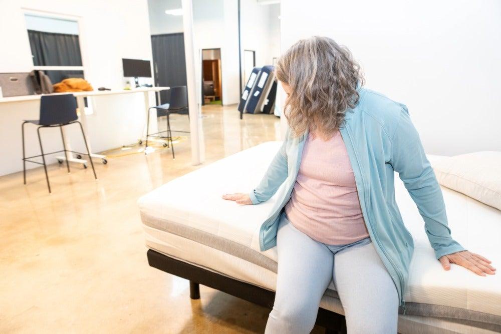 A woman sitting on the edge of the Helix Plus mattress