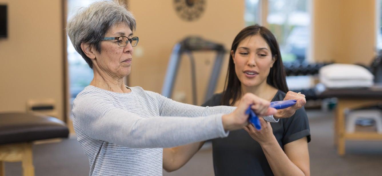 Physical therapist working with older woman using a resistance band