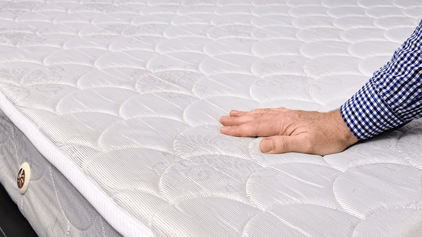 man's hand on top of a mattress