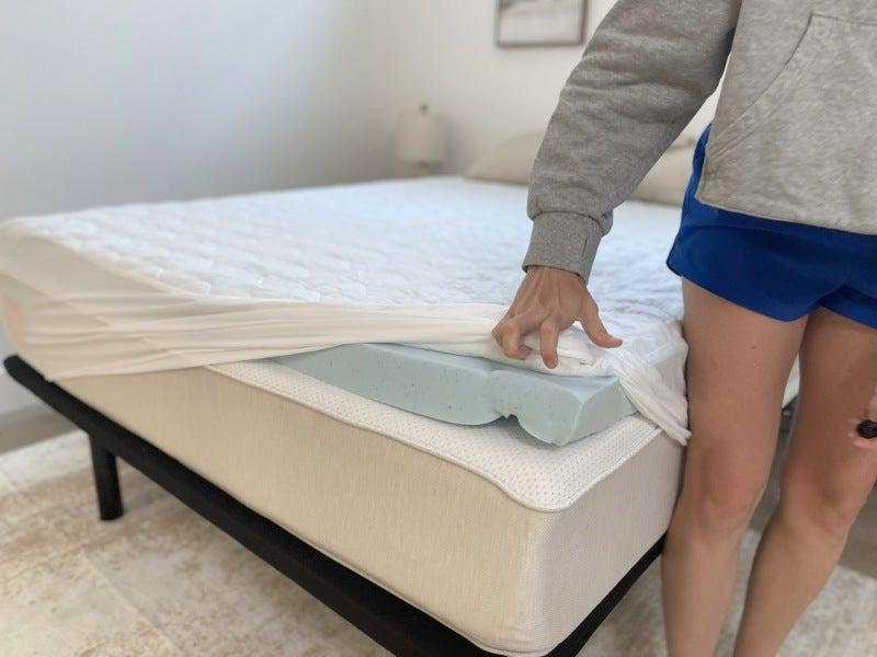 A person lifting the corner of a sheet to show the ViscoSoft mattress topper