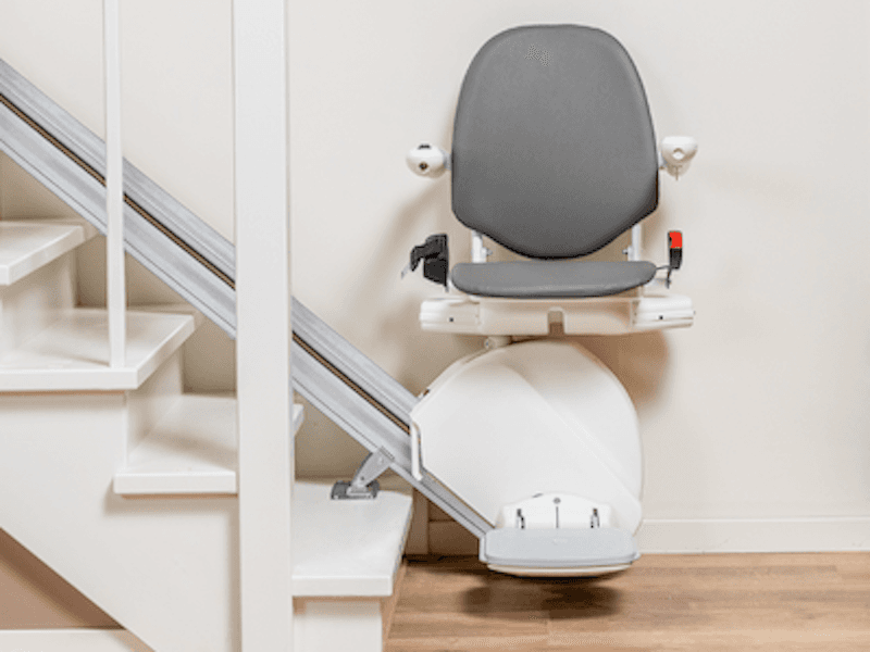 The Otolift stair lift at the bottom of a white staircase