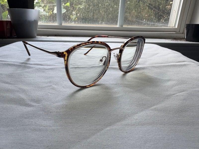 A pair of round tortoiseshell glasses on a white linen tablecloth