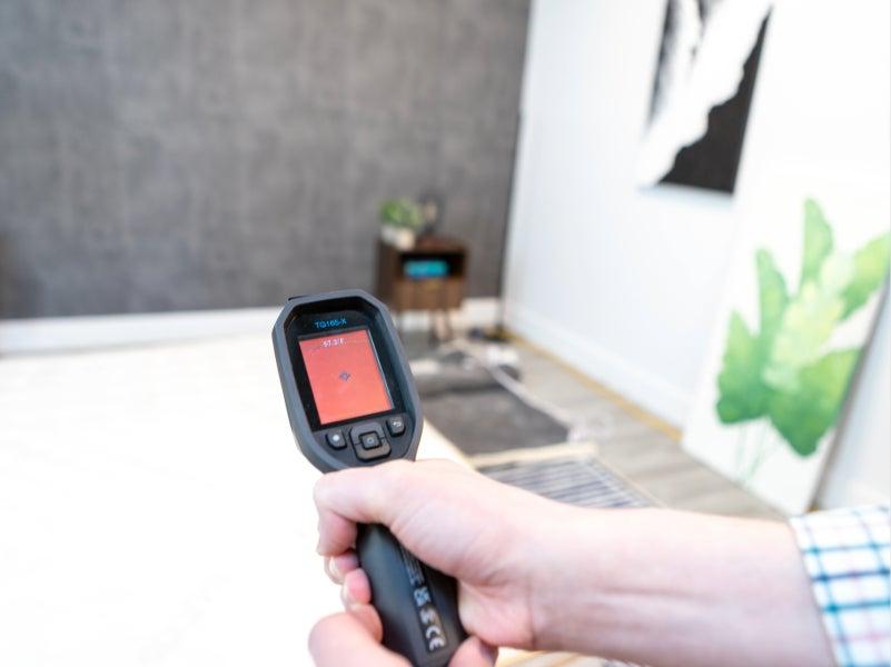 A hand holding a heat-sensing gun at the Brooklyn Bedding Aurora Luxe