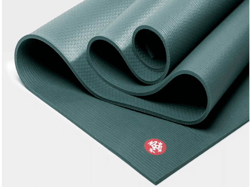 Partially unrolled green yoga mat showing the red circular Manduka logo