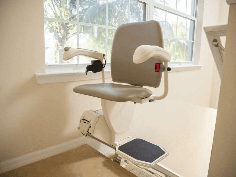 A Harmar stair lift at the top of an indoor flight of stairs