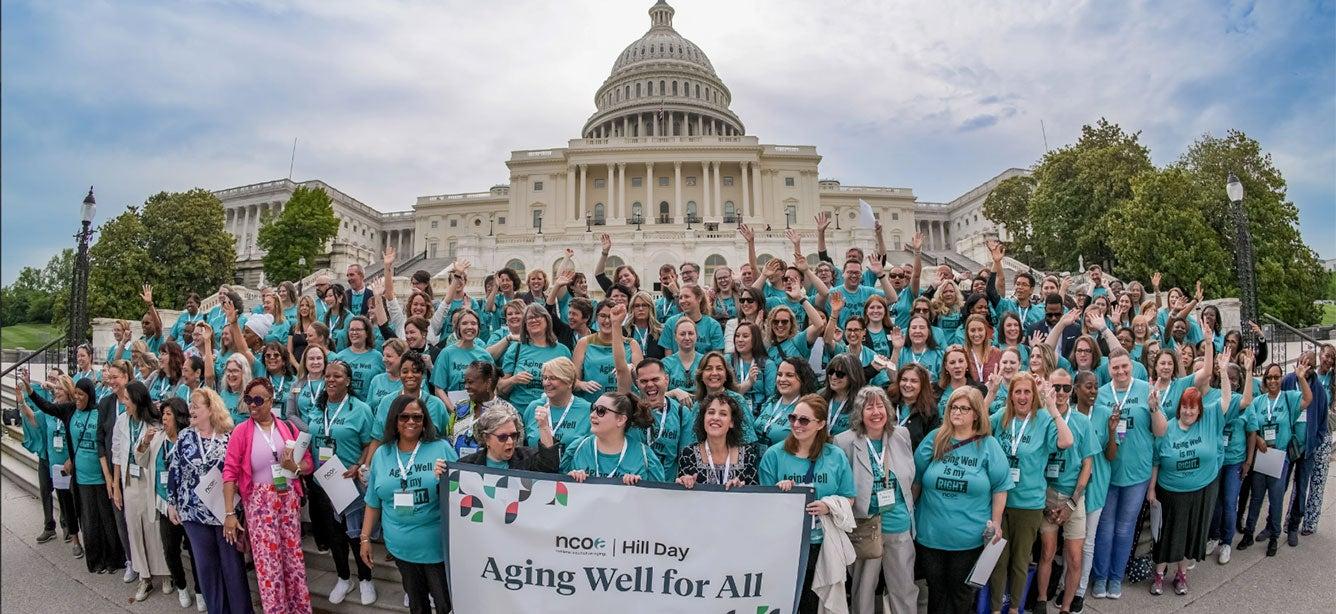 A large, diverse group of people is gathered on the steps of the Capitol building, all wearing matching teal shirts with the slogan "Aging Well is my RIGHT." They are part of the Age+Action 2024 Conference Hill Day event organized by NCOA. The participants are smiling, cheering, and raising their hands in solidarity, holding a banner that reads "Aging Well for All." The Capitol dome is prominently visible in the background, signifying the advocacy and unity of the group in promoting the rights and well-being of older adults.
