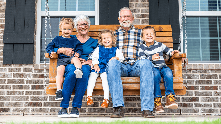 grandmother and grandfather on porch swing with two grandsons and a granddaughter