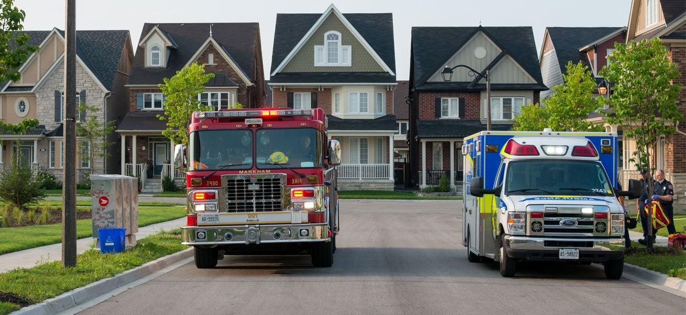 A fire trick and EMS vehicle are parked on a Surburbia/neighborhood street.