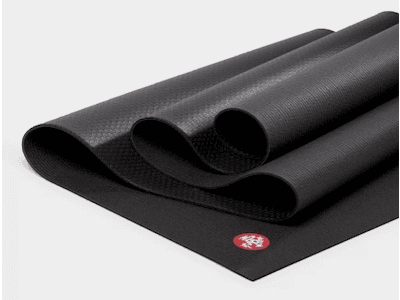 Folded yoga mat in black, showing red Manduka logo.