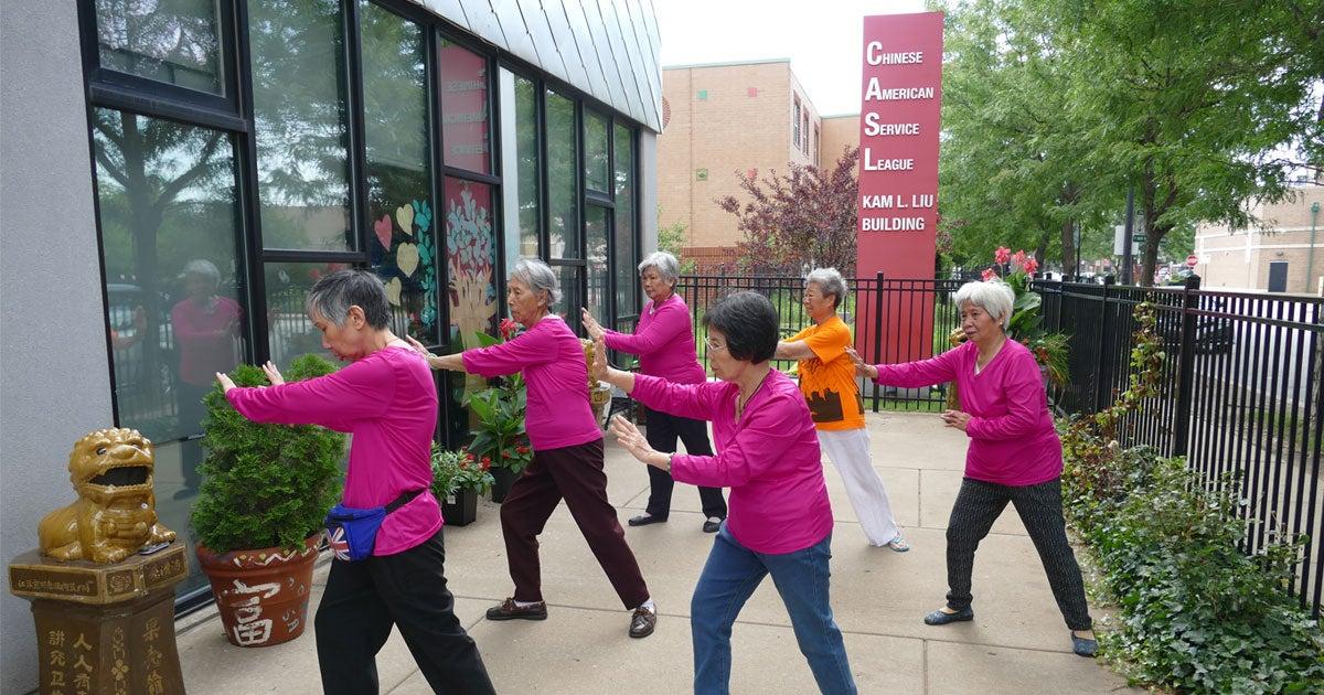 Chinese American women in pink shirts practicing tai chi outside