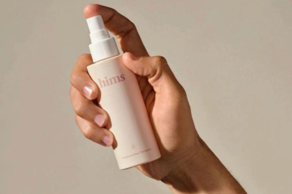 hand holding a bottle of Hims hair loss spray