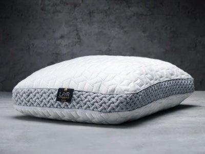 A white Luxome LAYR pillow without a pillowcase in front of a grey carpeted background