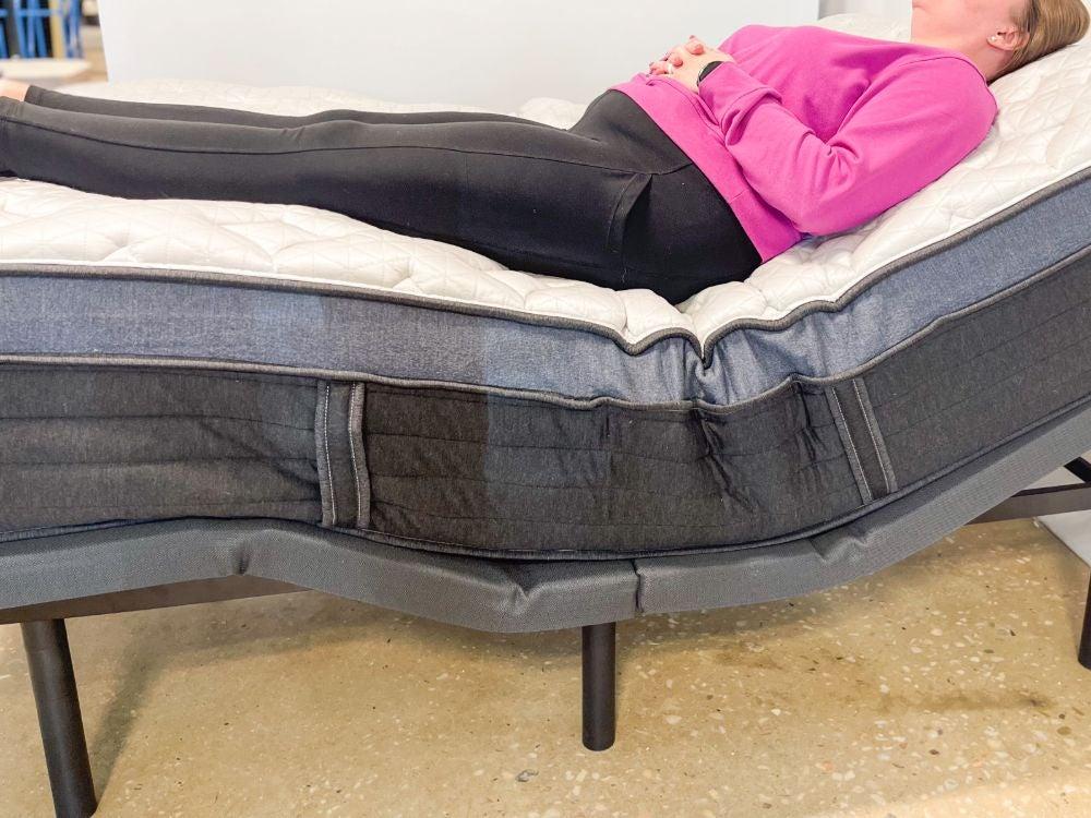 A woman lying on her back on the Helix Midnight Luxe mattress on an adjustable base