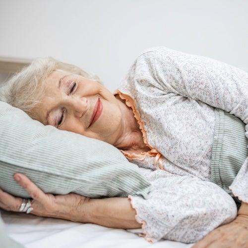 A woman lying in on her side in bed, smiling
