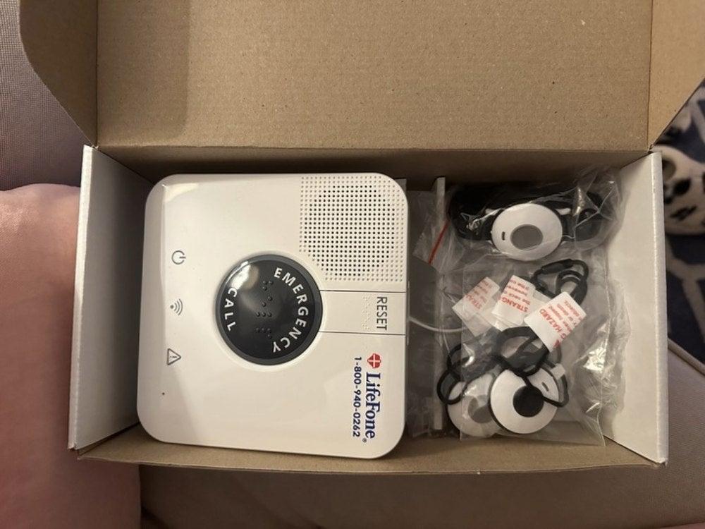 Open box containing LifeFone Home device and necklaces