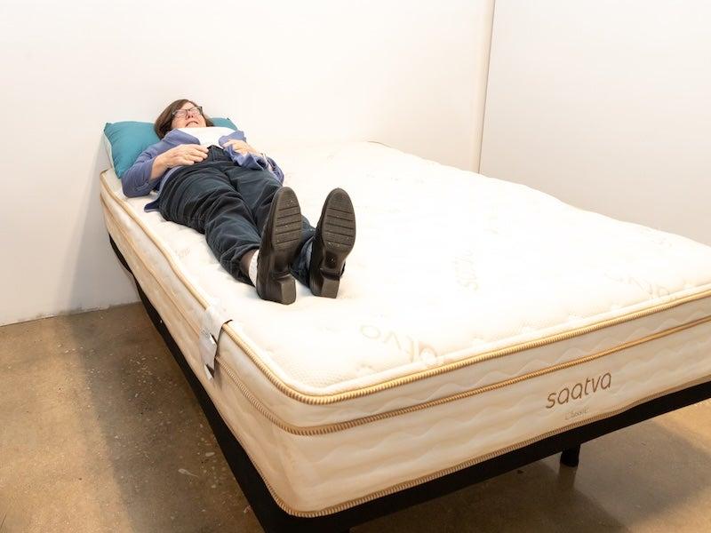 A woman lies on her back near the edge of the Saatva Classic Luxury Firm mattress