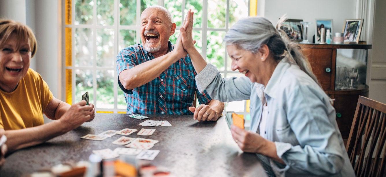 Three older adults playing cards.
