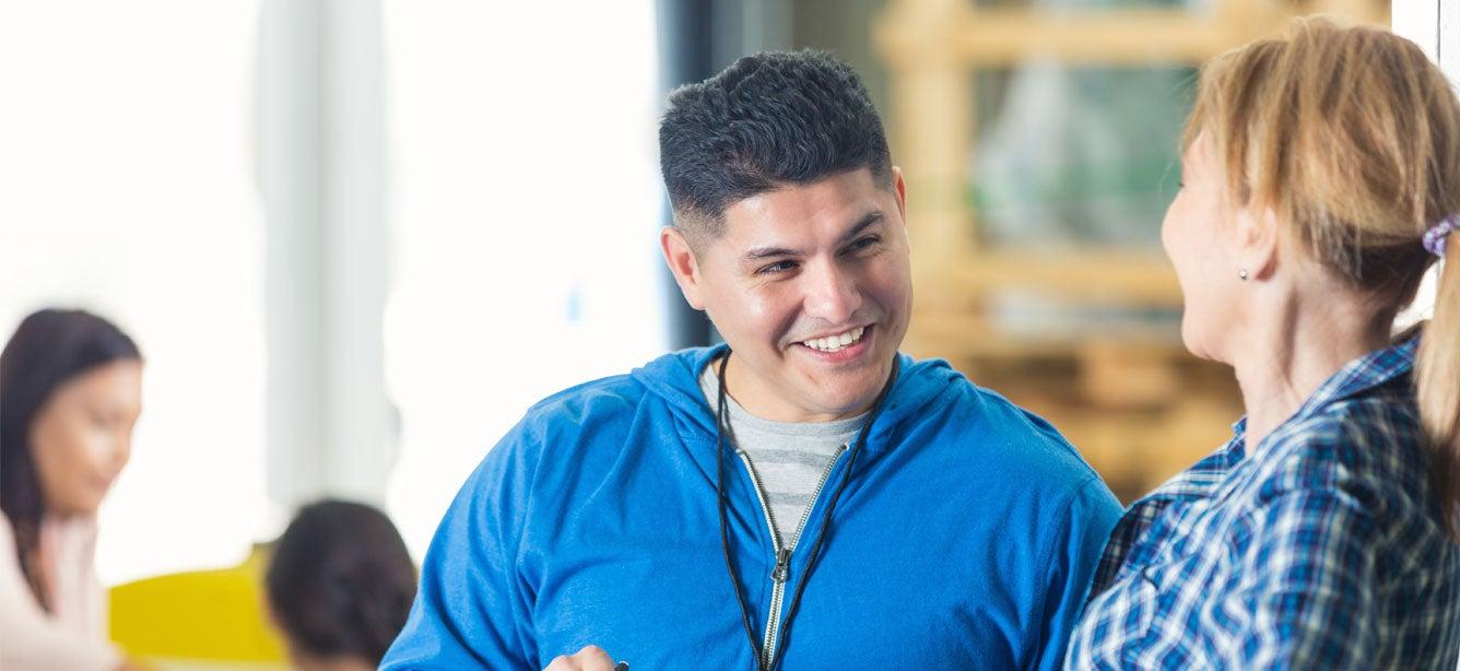 A mid adult professional discusses a volunteer list or inventory with co-director. He is pointing to the list on the clipboard.
