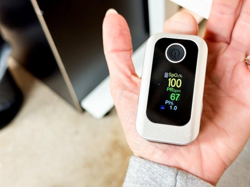 A woman wears the Oxiline XS Pro on her fingertip