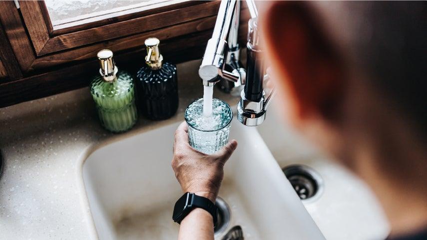 someone filling a water glass at a white sink