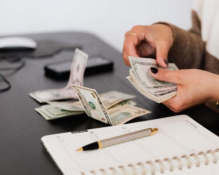 An older woman is seen counting her cash and also planning for the future.