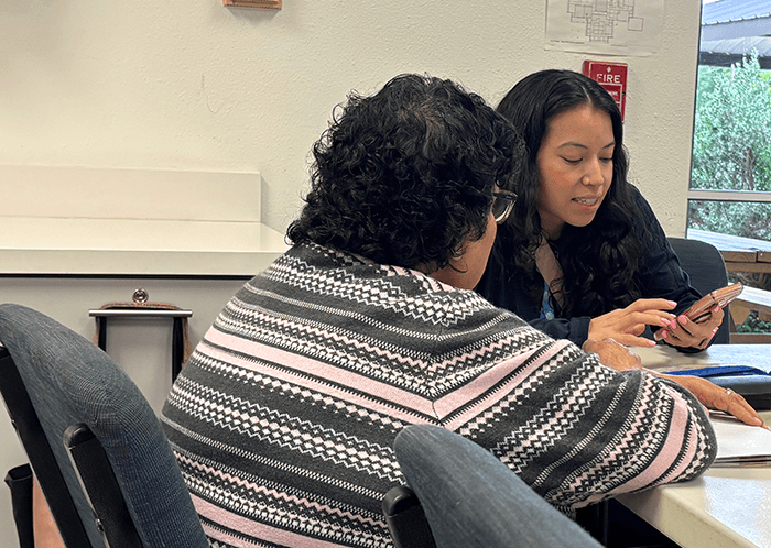 volunteer showing older woman features on a cellphone